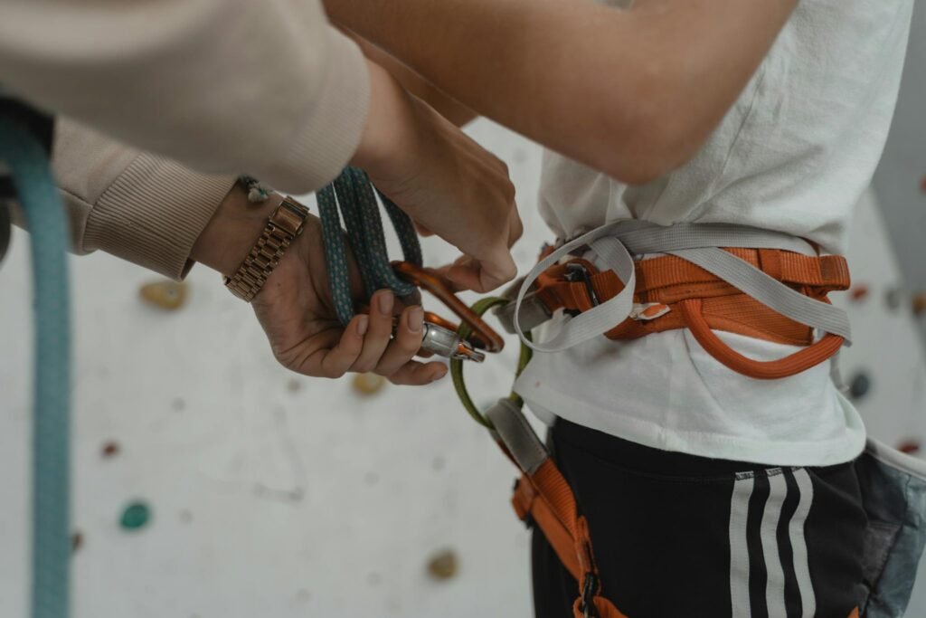 Detailed view of a rock climber preparing with harness and ropes. Indoor climbing setup.