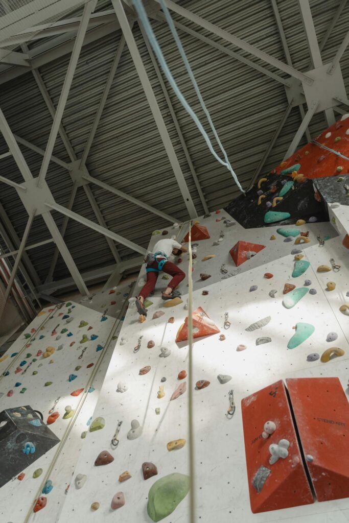 Dynamic shot of a climber scaling an indoor rock climbing wall, showcasing skill and fitness.