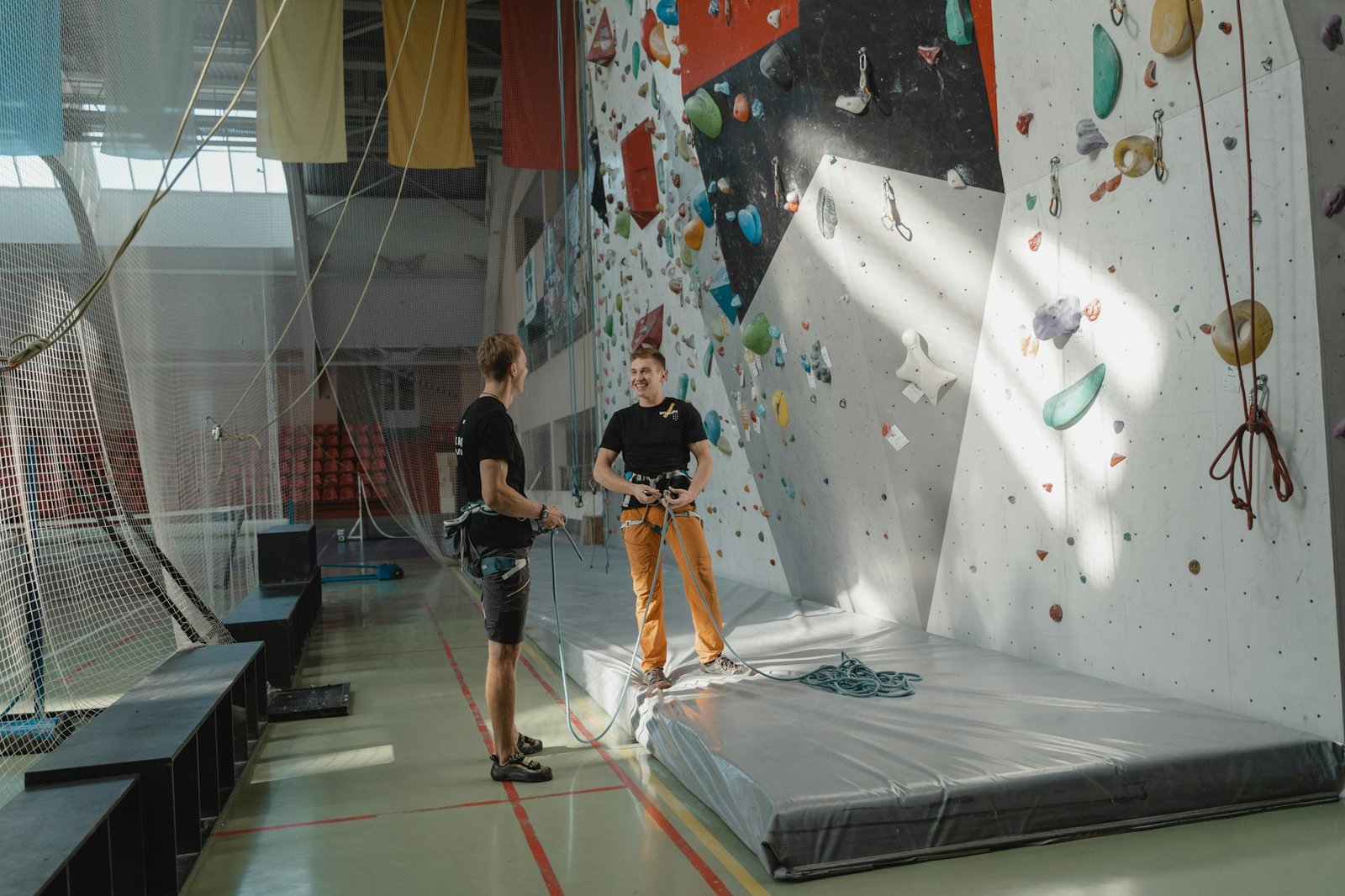 Two men preparing for indoor rock climbing at a climbing gym.